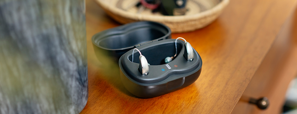 Image of hearing aids sitting in a charger on a desk